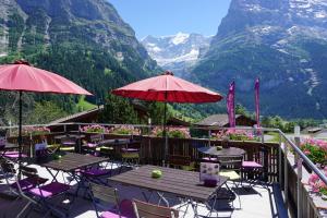 a patio with tables and chairs with mountains in the background at Hotel Alpenblick in Grindelwald