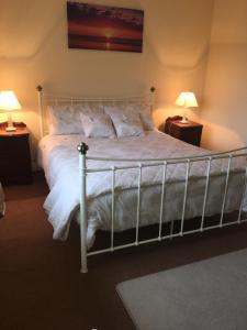 ウェストポートにあるCeol Na Maraのベッドルーム1室(白いベッド1台、ランプ2つ付)