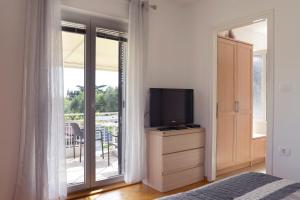 a bedroom with a television on a dresser with a balcony at Apartments and Rooms Oražem Zoro in Portorož