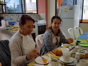 dos mujeres sentadas en una mesa comiendo comida en Hostal Casa Cascada, en Puerto Ayora