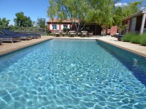 a swimming pool with blue water in front of a house at Les Terrasses de Valensole in Valensole
