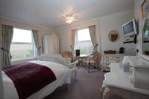 1 dormitorio con cama, escritorio y mesa en Fernhill Hotel, en Lyme Regis