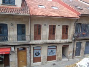 stary budynek z czerwonym dachem i balkonem w obiekcie Albergue Parroquial Santiago Apostol de Redondela w mieście Redondela