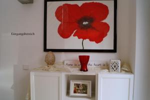 una flor roja sobre armarios blancos en una habitación en Ferienwohnung Casa Di Lago, en Heinsberg