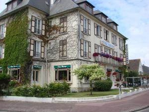 - un grand bâtiment en pierre avec du lierre sur une rue dans l'établissement Chez-Marion, à Merville-Franceville-Plage