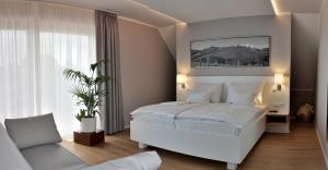 1 dormitorio con cama blanca y sofá en Weinrefugium Brolli en Gamlitz