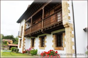 a building with a balcony and flowers on the side at Posada La Estela Cántabra in Toñanes