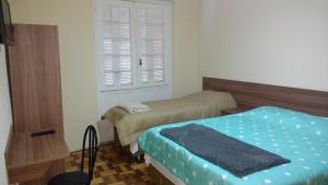Habitación pequeña con 2 camas y ventana en Lotus Hotel & Hostel, en Porto Alegre