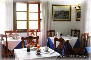 a dining room with two tables and two windows at Posada La Estela Cántabra in Toñanes