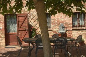 Podere Fontegallo في كاستيغليون ديل لاغو: طاولة وكراسي وشجرة أمام المبنى