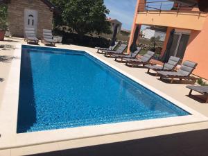 a swimming pool with chairs and a house at Apartments Dalmatina in Zaton