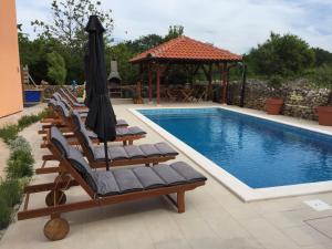 a pool with chairs and a gazebo next to a pool at Apartments Dalmatina in Zaton