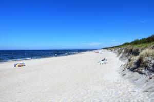 a group of people walking on a sandy beach at Przy Mickiewicza in Dziwnów +3 photos