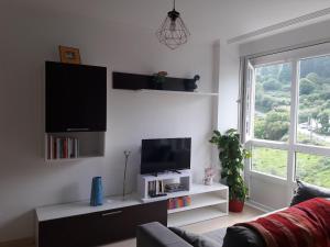 Una sala de estar con un televisor de pantalla plana en una pared. en Viveiro, en Viveiro