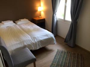 a bedroom with a bed and a chair and a window at UusAllika Puhkemaja in Haapsalu