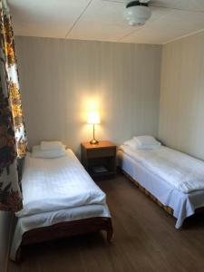 two beds in a room with a lamp on a table at UusAllika Puhkemaja in Haapsalu +6 photos