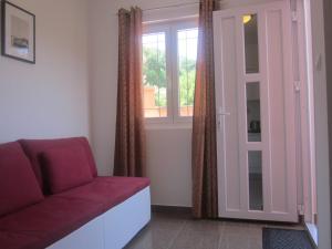 a living room with a red couch and a window at Apartments Danilo Kažanegra in Sveti Stefan