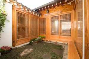 Holzzimmer mit Holztüren und Fenstern mit Pflanzen in der Unterkunft Bukchonae in Seoul