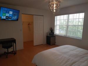 um quarto com uma cama branca e uma televisão na parede em Sawgrass em Sunrise