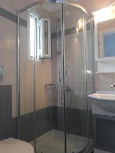 y baño con ducha y puerta de cristal. en Medusa Accommodation, en Livadakia