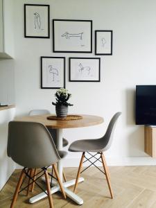 a dining room table and chairs with drawings on the wall at Apartament Kolska in Warsaw