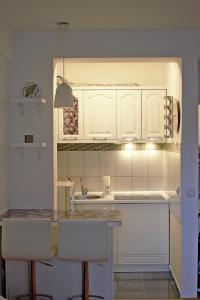 una cocina con armarios blancos y taburetes de barra blanca en Trident Apartments en Niš