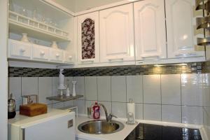 una cocina con armarios blancos y fregadero en Trident Apartments en Niš