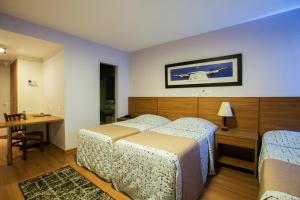 Gallant Hotel في ريو دي جانيرو: غرفة نوم بسريرين وطاولة ومكتب