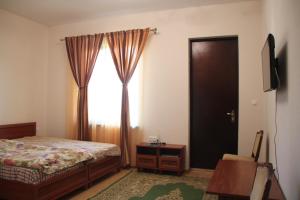1 dormitorio con cama, ventana y TV en АМРАПХА, en Gudauta