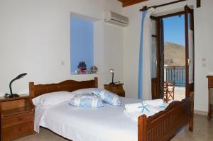 a bedroom with a bed with white sheets and a window at Kamares Studios in Symi