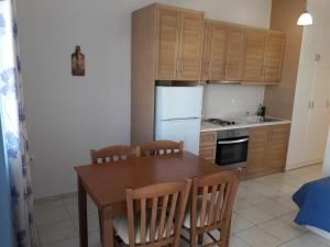 uma cozinha com uma mesa de madeira e um frigorífico branco em Medusa Accommodation em Livadakia