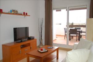 a living room with a tv on a wooden dresser at Golf Course View Penthouse in El Romero