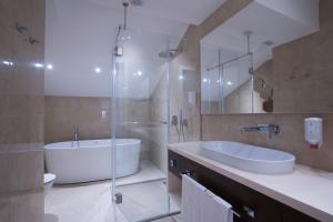 a bathroom with a tub and a sink and a shower at Hotel Riva by Aycon in Petrovac na Moru