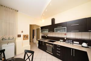 a kitchen with black cabinets and white tile floors at Rox Central Apartments 2 in Timişoara