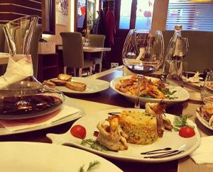 a table with plates of food and glasses of wine at Hotel Vila Alfa in Korçë