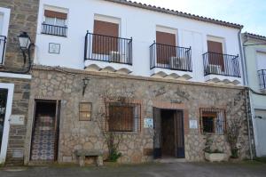 托雷霍內爾魯維奧的住宿－Alojamiento la cañada monfrague，一座古老的石头建筑,设有窗户和阳台