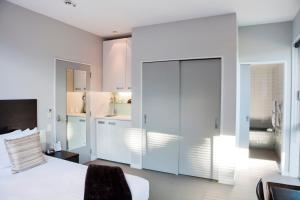 
a hotel room with a white bed and white walls at Swiss-Belsuites Pounamu Queenstown in Queenstown
