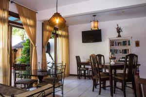 uma sala de jantar com mesa e cadeiras e uma televisão em Porto dos Casais Guest House Itacaré em Itacaré