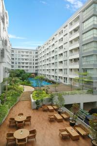 ein großes Apartmenthaus mit Tischen und Bänken in der Unterkunft Kyriad Hotel Airport Jakarta in Tangerang