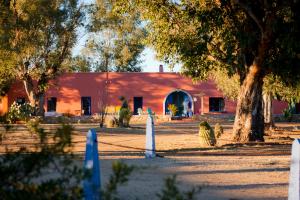 un bâtiment rouge avec un arbre devant lui dans l'établissement Rancho de la Osa Guest Ranch, à Sasabe