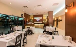 ein Restaurant mit weißen Tischen und Stühlen sowie einer Küche in der Unterkunft Swiss Hotel Apartment in Kuala Belait + 30 Fotos