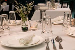 a table with white plates and vases with flowers at Swiss Hotel Apartment in Kuala Belait
