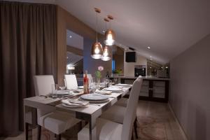 a dining room table with white chairs and a kitchen at Hotel Riva by Aycon in Petrovac na Moru