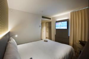 a hotel room with a bed and a flat screen tv at ibis Styles Kortrijk Expo in Kortrijk