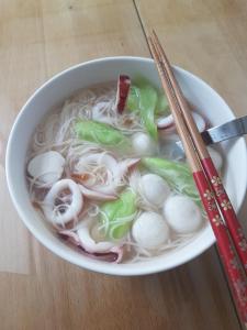 a bowl of soup with noodles and mushrooms and chopsticks at Travel Light House in Magong