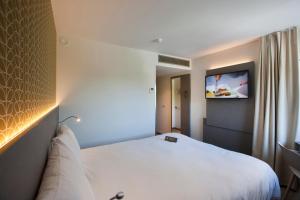 Habitación de hotel con cama y TV en la pared en ibis Styles Kortrijk Expo en Kortrijk