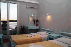 a bedroom with two beds and a mirror at Hotel Paros in Parikia