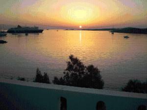 a sunset over a lake with a boat in the water at Hotel Paros in Parikia