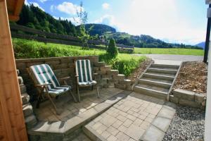two chairs sitting on a patio with a stone wall at Chalet Apartment Leogang in Leogang