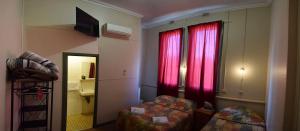 a small room with a bed and a window with red curtains at The Palace Hotel Kalgoorlie in Kalgoorlie